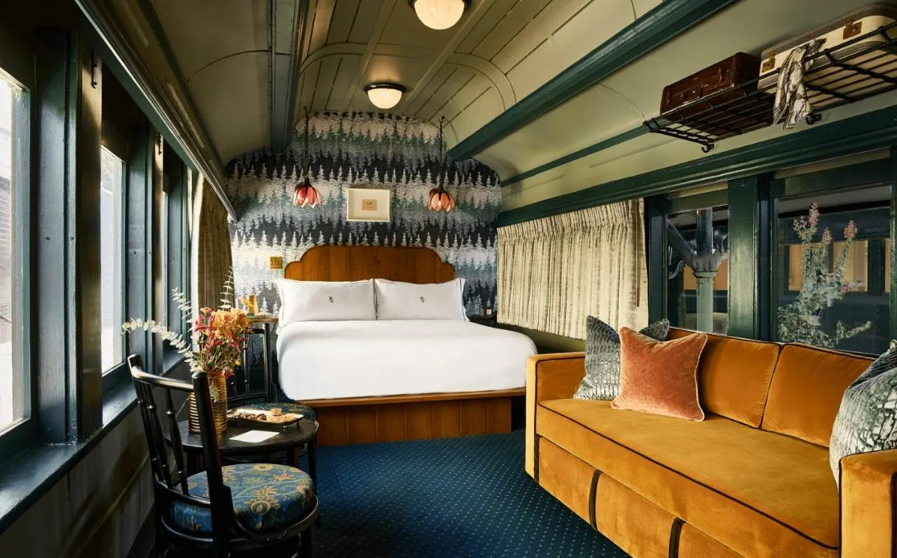 a queen sized bed and couch inside the hotel chalet at the choo choo inside a train car with modern design