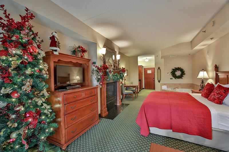king sized bed with red sheets and christmas decor as well as christmas tree  at the inn at the christmas place in pigeon forge tn 