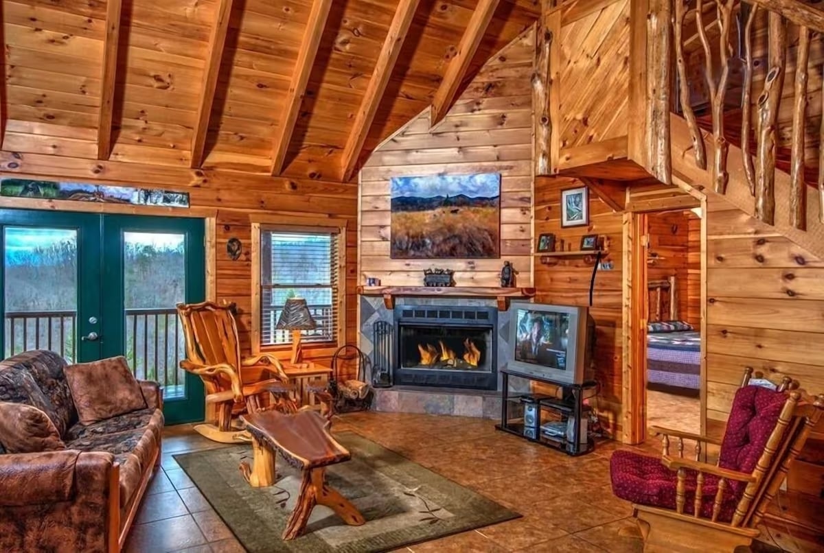 cozy living room of the 1 of a kind log cabin in sevierville tn with wood interior and cozy fireplace with large windows overlooking the smoky mountains