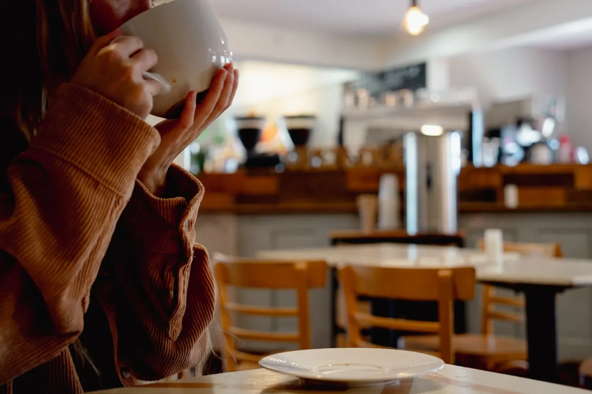 woman sipping on hot coffee at open doors cofeehouse in johnson city tn