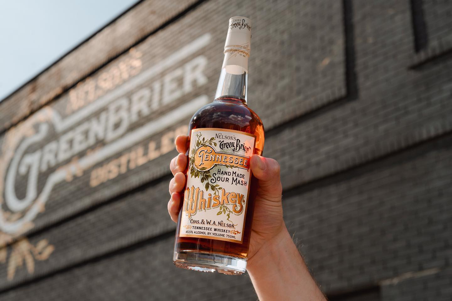 person holding a bottle of hand made sour mash whiskey from green brier distillery in Nashville TN 
