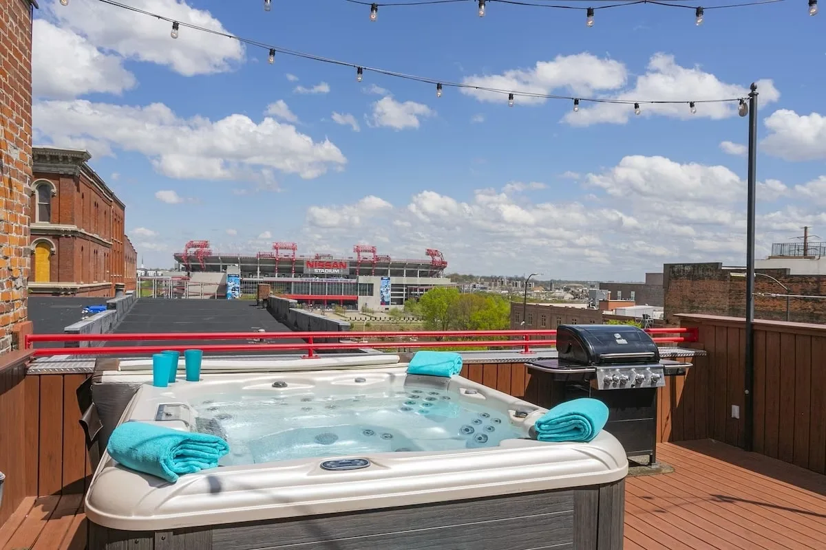a hot tub and grill on top of a rooftop in Nashville overlooking the Nissan stadium 
