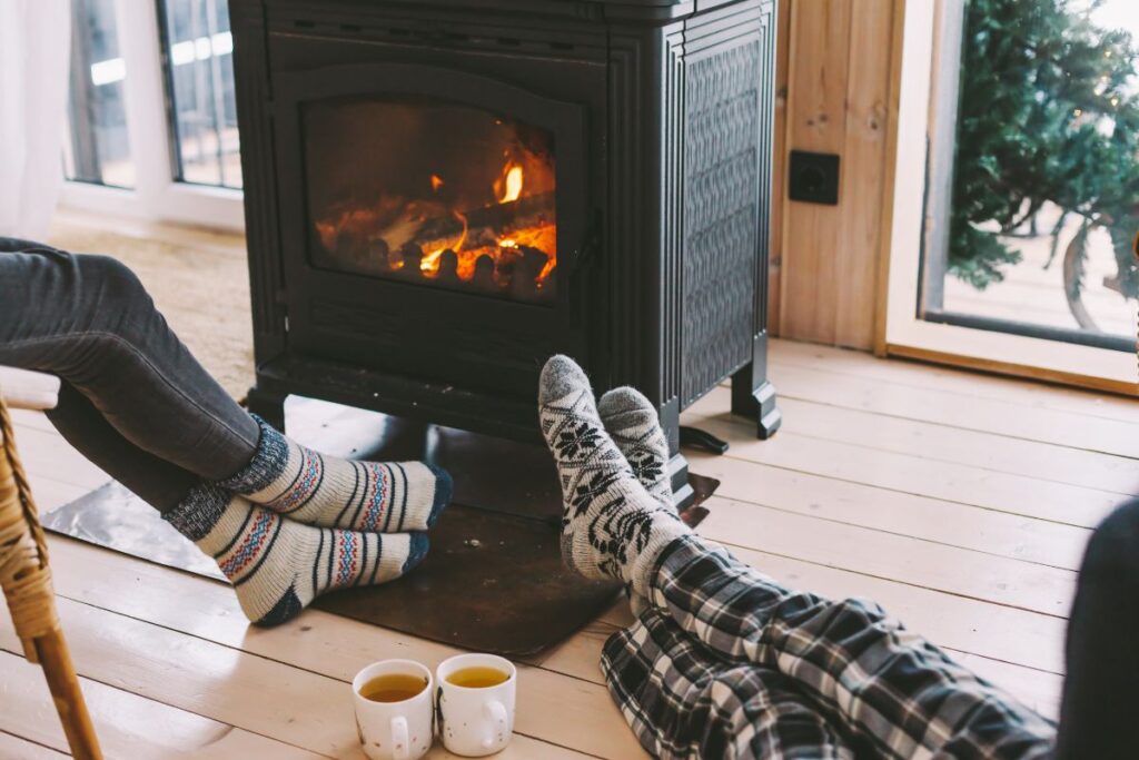 People sitting around a fireplace with cups of hot coffee in a cozy cabin